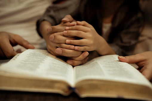 a kid reading the holy bible with guide by parents