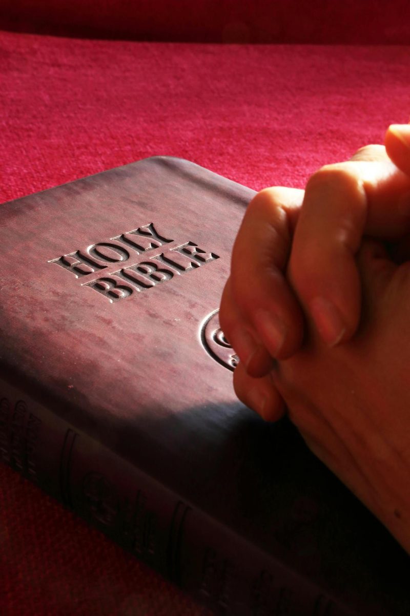 The bible covered by folded hands.